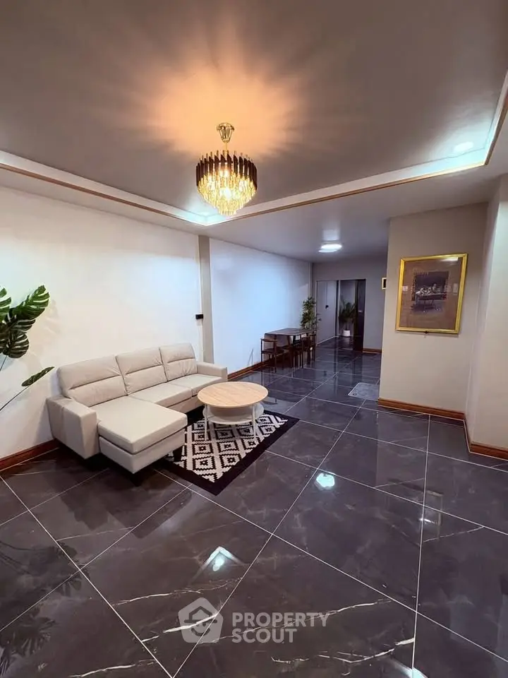 Elegant living room with modern chandelier and stylish furniture, perfect for relaxation and entertaining.