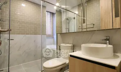 Modern bathroom with glass shower, elegant tiles, and stylish fixtures.