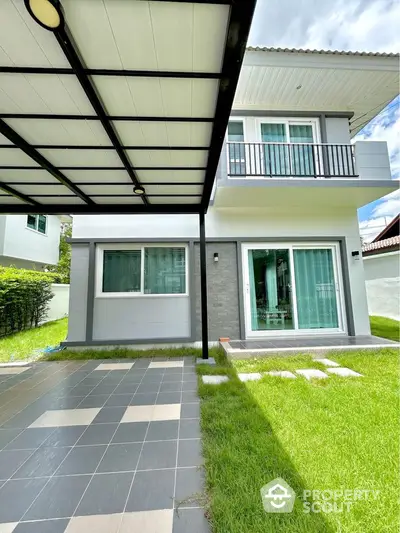 Modern two-story house with green lawn and covered parking area