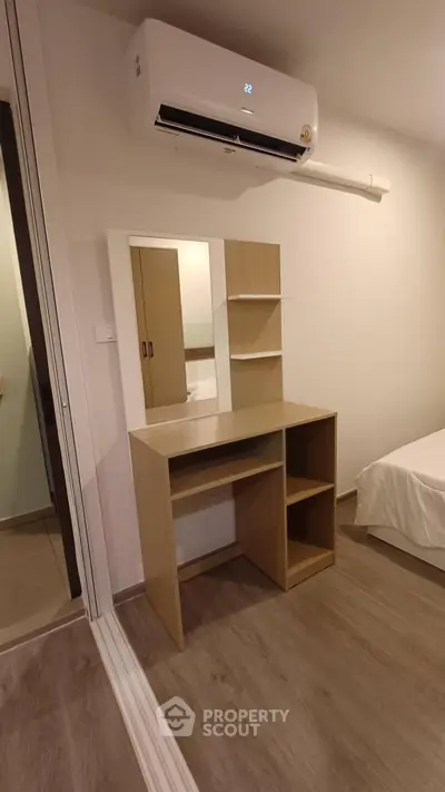 Modern bedroom with sleek wooden vanity and air conditioning unit, perfect for comfort and style.