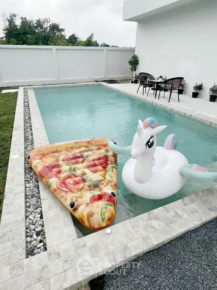 Luxurious private pool with playful inflatables in modern backyard setting.