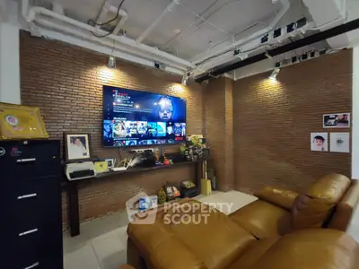Cozy living room with leather seating and exposed brick wall featuring a large TV.