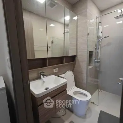 Modern bathroom with glass shower and sleek vanity in contemporary apartment.