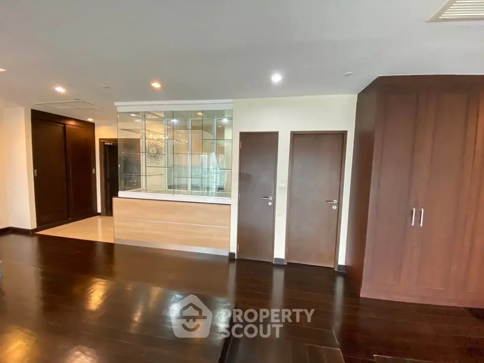 Spacious modern living room with dark wood flooring and built-in storage