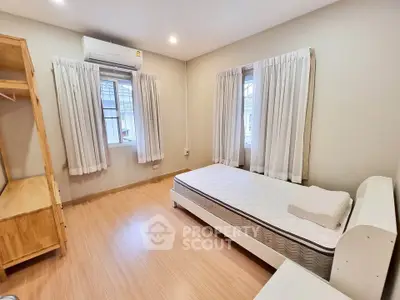 Spacious bedroom with natural light, wooden flooring, and modern furnishings for a cozy living experience.