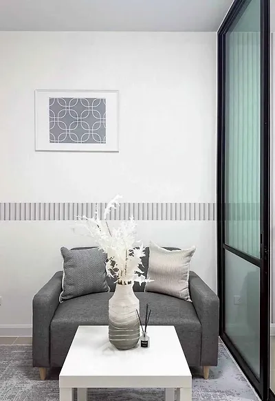 Modern living room with stylish gray sofa, decorative pillows, and elegant vase on a white coffee table.