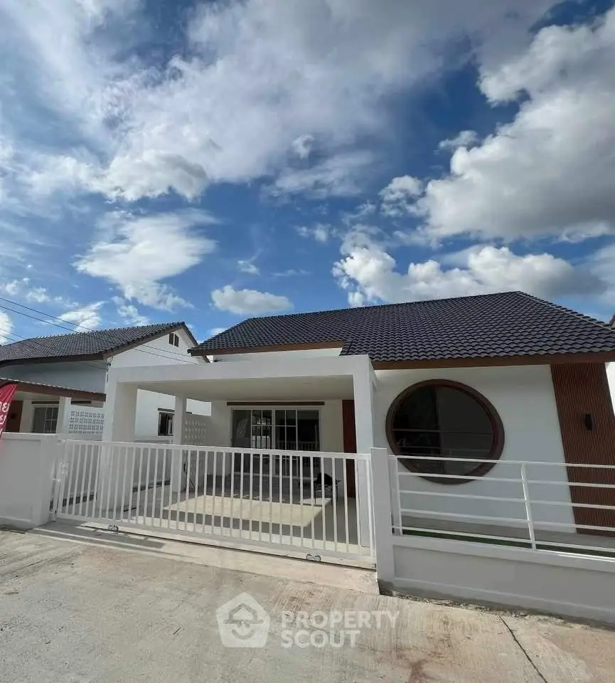 Modern single-story house with unique circular window and sleek design under a vibrant blue sky.
