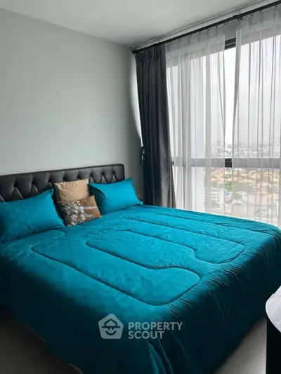 Modern bedroom with large window and teal bedding offering city views.