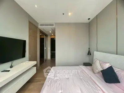 Modern bedroom with sleek design and wall-mounted TV, featuring elegant lighting and neutral tones.