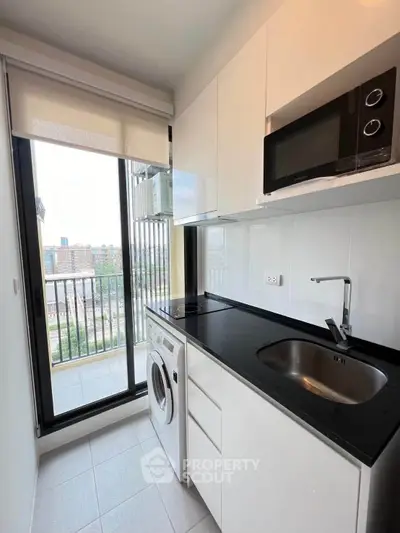 Modern kitchen with sleek appliances and balcony view in urban apartment