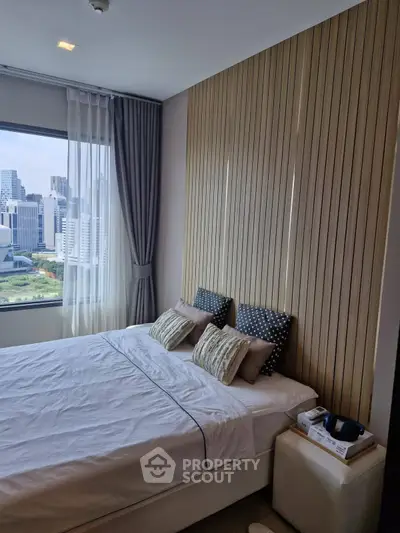 Modern bedroom with city view, featuring stylish decor and large window for natural light.