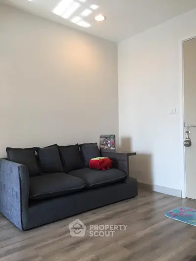 Modern living room with cozy gray sofa and wooden flooring, perfect for relaxation.