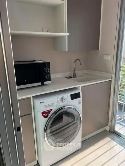 Modern compact kitchen with built-in appliances and washing machine, featuring sleek cabinetry and natural light.