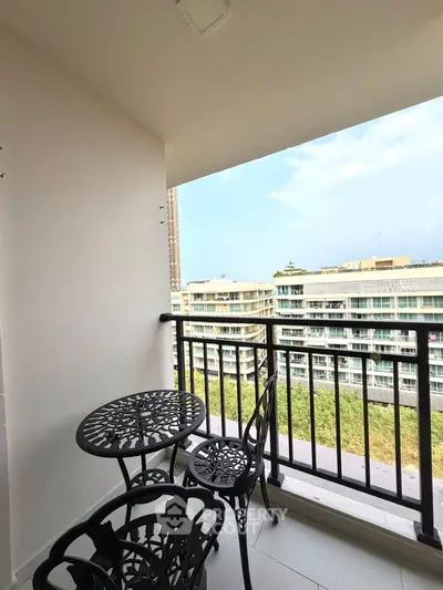Charming balcony with elegant iron furniture and scenic view of modern buildings.