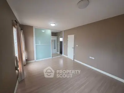 Spacious empty room with wooden flooring and large windows, ideal for customization.