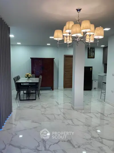 Elegant open-plan living and dining area with modern chandelier and marble flooring.