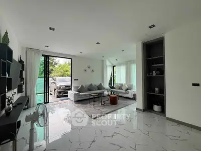 Spacious modern living room with sleek design and large windows offering natural light and garden view.