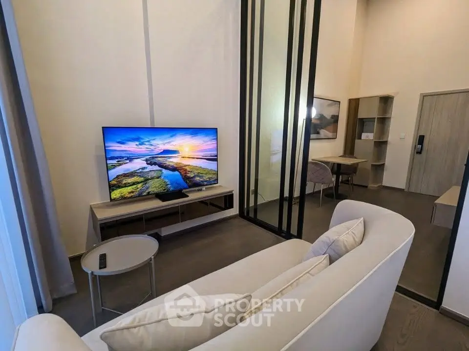 Modern living room with sleek design and large TV, featuring a cozy sofa and stylish decor.