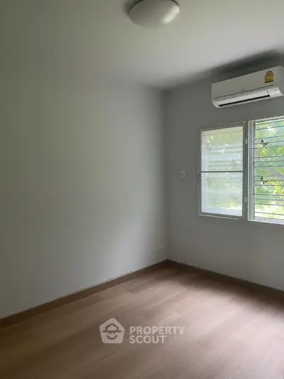 Spacious empty room with air conditioning and large window, perfect for customization.