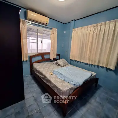 Cozy bedroom with blue tiled walls and air conditioning, featuring a wooden bed and large window.