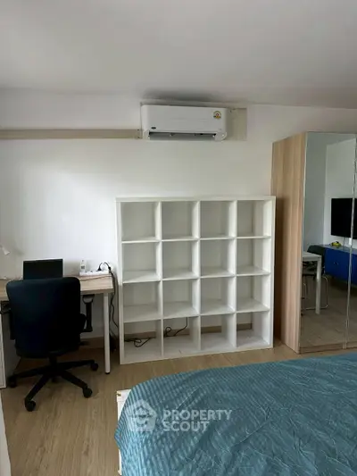 Modern bedroom with stylish shelving and workspace, featuring air conditioning and a cozy bed.