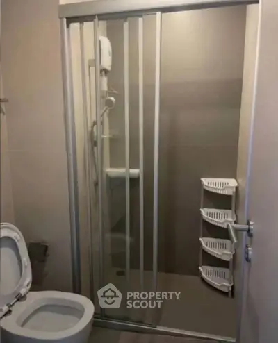 Compact bathroom with shower enclosure and toilet, ideal for efficient space utilization.