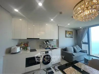 Modern open kitchen and living room with ocean view and elegant chandelier