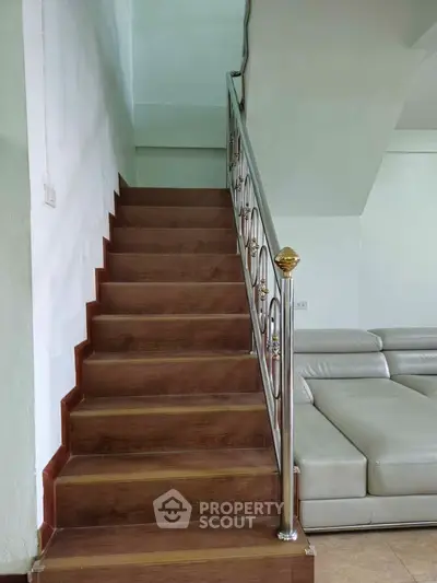 Modern staircase with elegant railing beside a sleek leather sofa in a stylish living room.