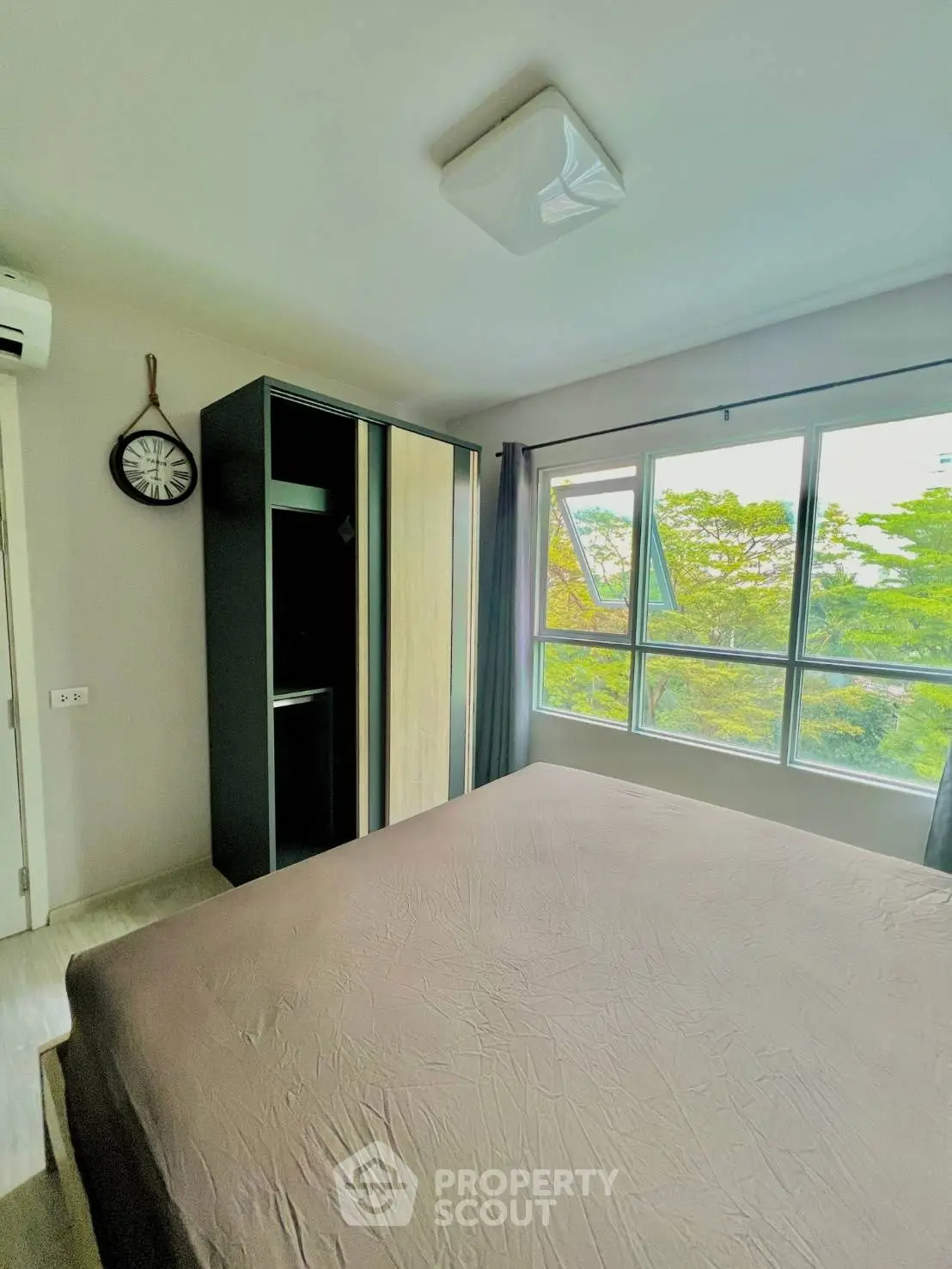 Bright bedroom with large window and modern wardrobe, offering serene garden views.