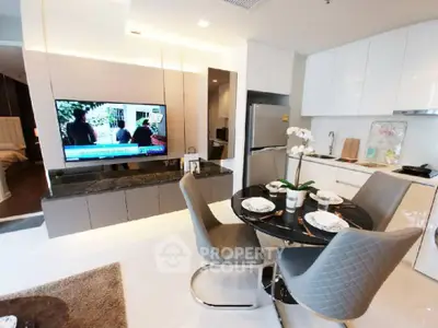 Modern open-plan living room and kitchen with sleek furniture and large TV
