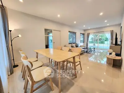 Spacious modern living room with elegant dining area and large windows offering garden views.