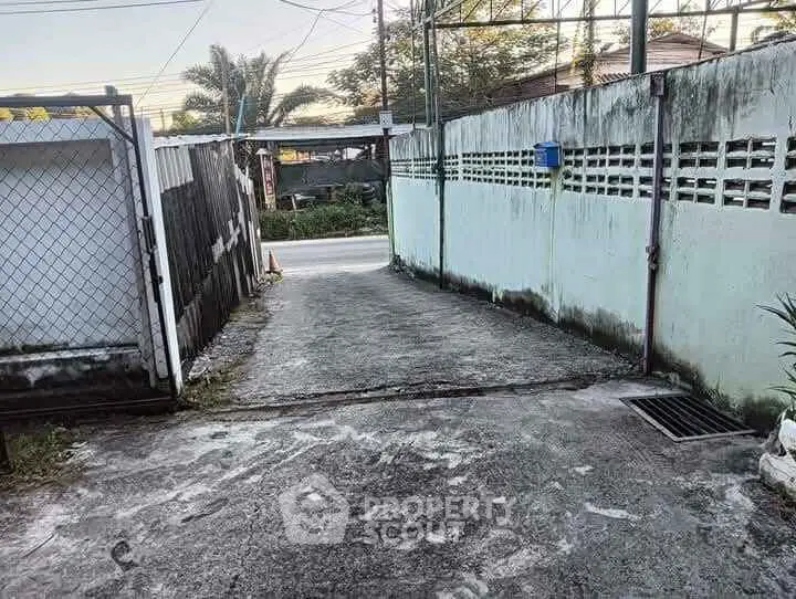 Charming driveway entrance with rustic gate and lush greenery, perfect for a cozy home.