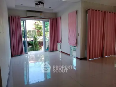 Spacious living room with large windows and pink curtains, offering garden view.