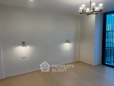 Spacious empty room with modern lighting and large window, perfect for customization.