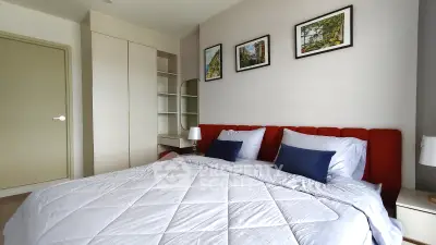 Modern bedroom with stylish red headboard and cozy bedding, featuring elegant wall art and built-in storage.