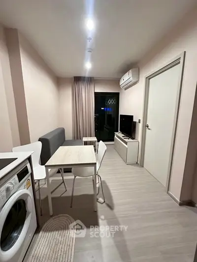 Modern living room with dining area and washing machine in compact apartment.