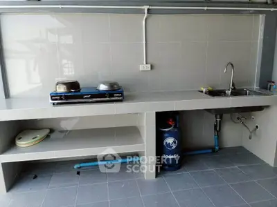 Modern kitchen with gas stove and sink, featuring sleek tile backsplash and ample counter space.