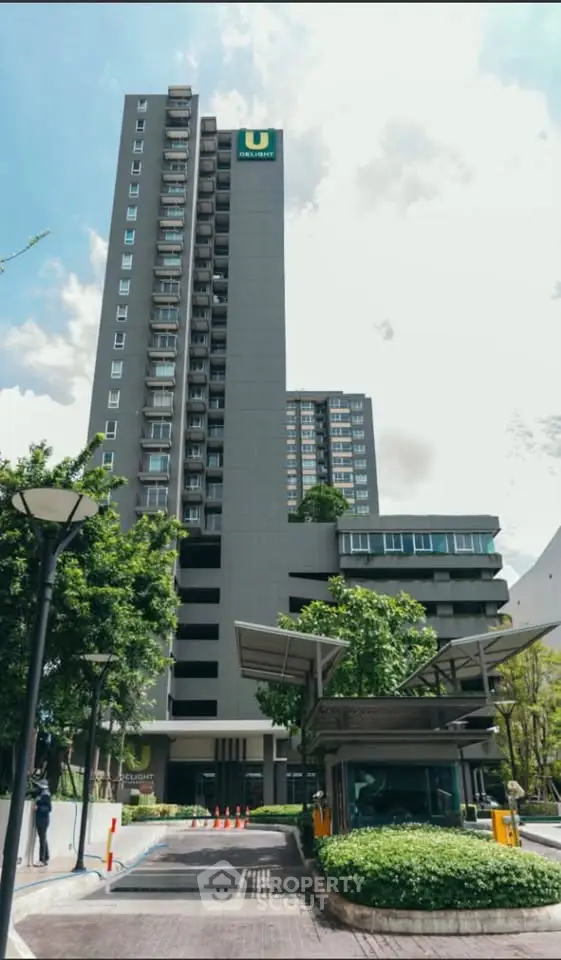 Modern high-rise building with lush greenery and clear blue sky, showcasing urban living at its finest.