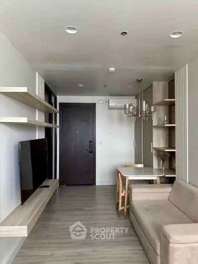 Modern living room with sleek TV setup and elegant dining area in a stylish apartment.