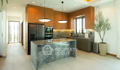 Luxurious modern kitchen with marble island and high-end appliances in a spacious open layout.
