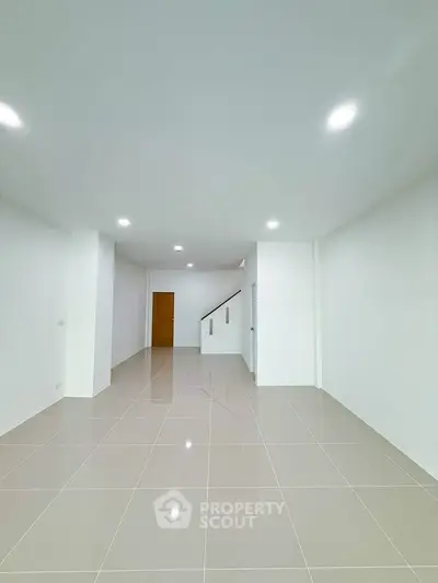 Spacious minimalist interior with glossy tiled flooring and recessed lighting, ideal for modern living.