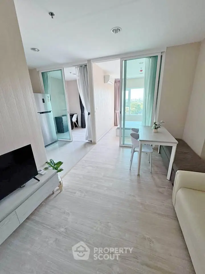 Modern open-plan living room with sleek furniture and large windows offering natural light.