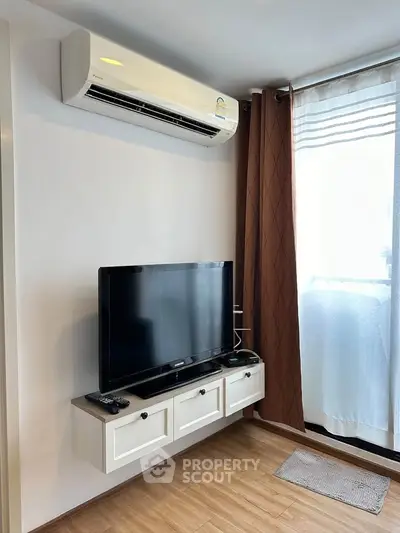 Modern living room with wall-mounted TV and air conditioning, featuring elegant curtains and wooden flooring.