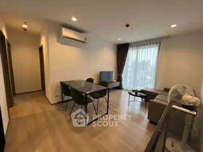 Modern living room with dining area, featuring sleek furniture and large window with city view.