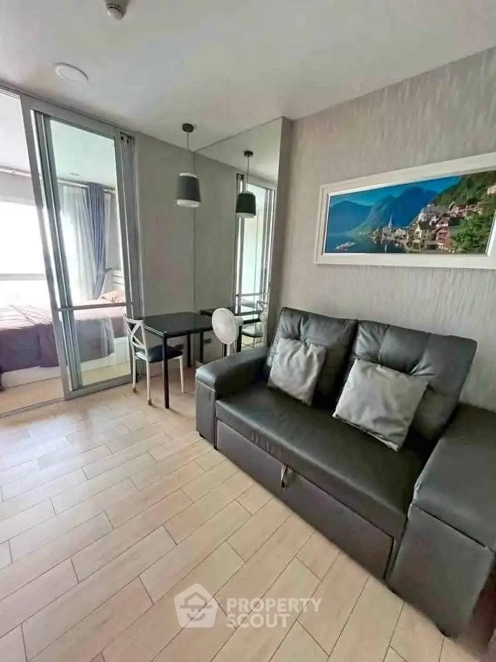 Modern living room with sleek sofa and dining area, featuring large windows and stylish decor.
