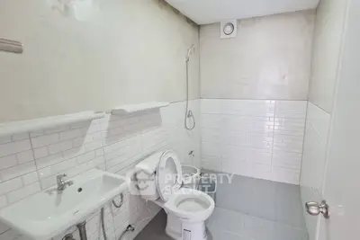 Modern minimalist bathroom with white subway tiles and sleek fixtures.