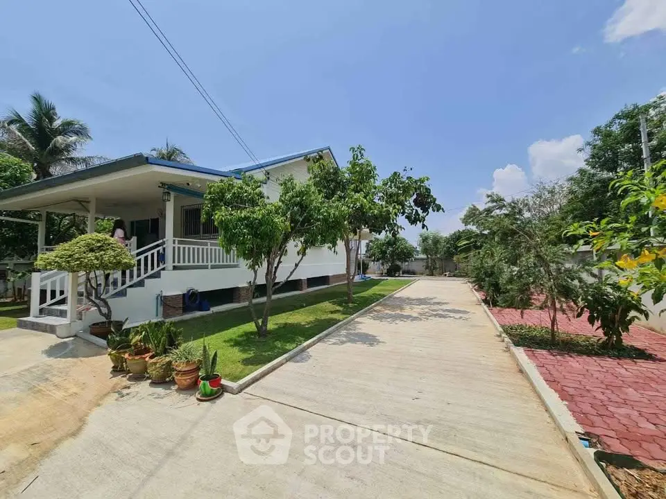 Charming single-story home with lush garden and spacious driveway under clear blue skies.