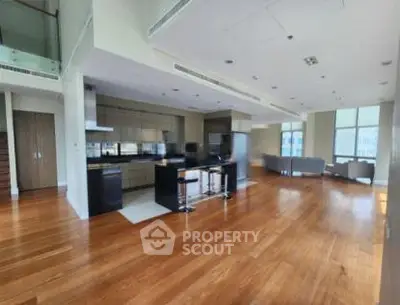 Spacious open-plan living area with modern kitchen and hardwood floors in luxury apartment.