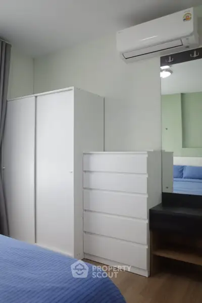 Modern bedroom with sleek white furniture and air conditioning