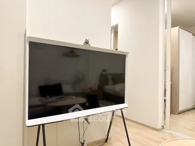 Modern living room with sleek TV setup and cozy bedroom view, perfect for urban living.